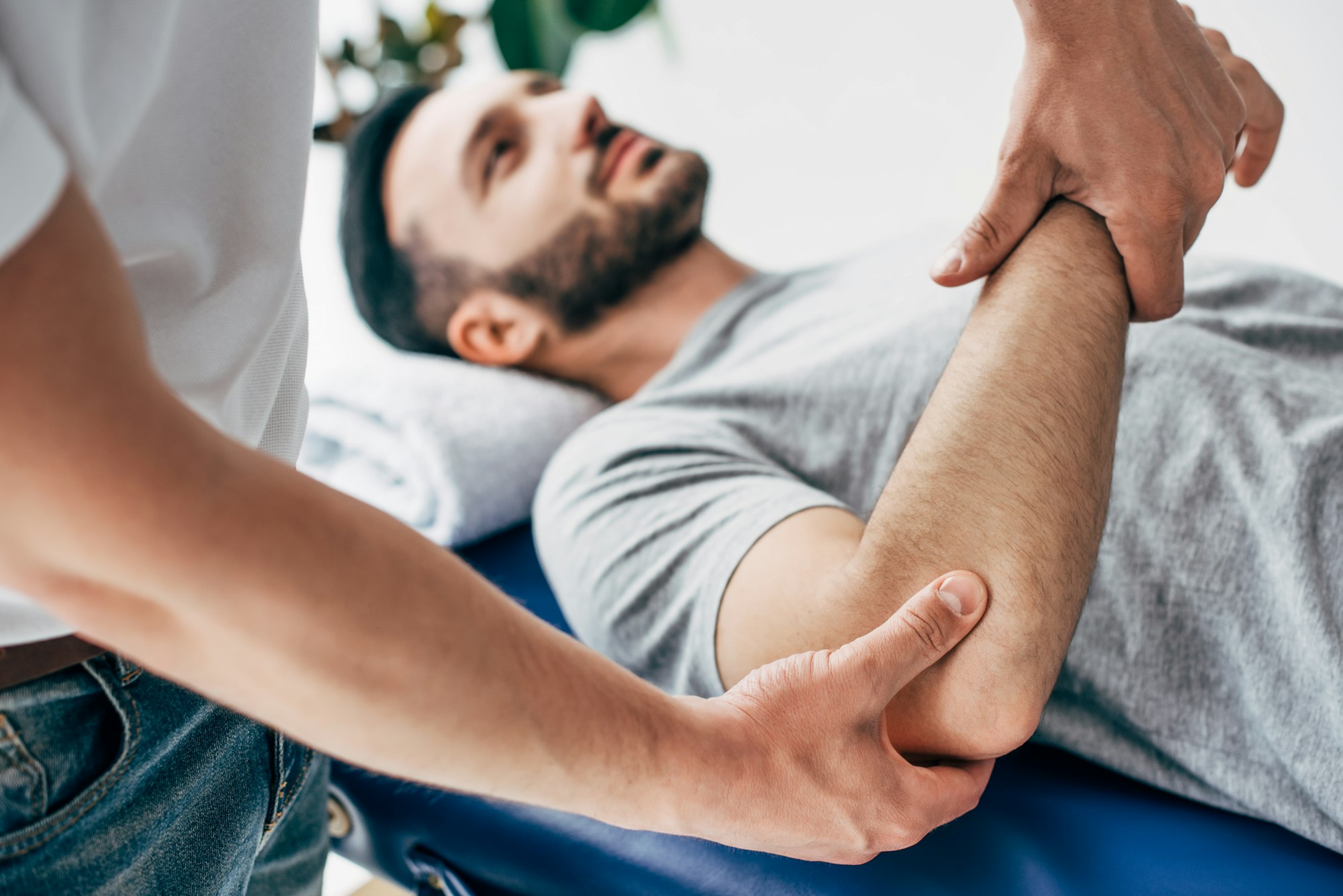 selective focus of chiropractor massaging arm of patient in hospital